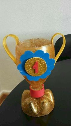 a gold trophy with a blue flower on it's head sitting on a table