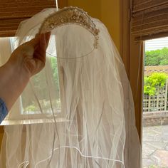 the veil is being held up by a person wearing a tiara on their head