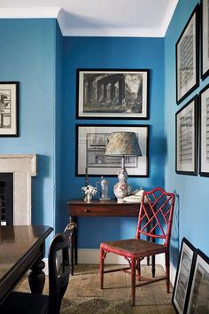 a blue room with pictures on the wall and a chair in front of a desk