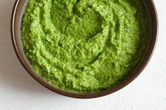 a bowl filled with green guacamole sitting on top of a white table