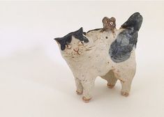 a ceramic cat figurine with two cats on it's back and the other one standing up