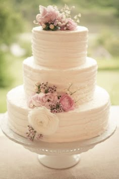 a white wedding cake with pink flowers on top