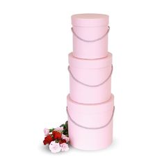 three pink boxes stacked on top of each other with flowers in the middle next to them