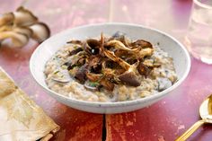 a bowl of oatmeal with mushrooms in it on top of a wooden table