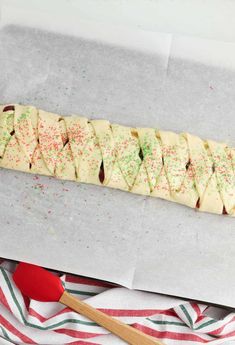 a long pastry with sprinkles on it and a wooden spoon next to it