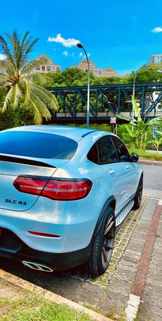 the rear end of a blue mercedes c - class coupe parked in front of a palm tree