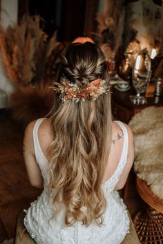 a woman with long hair sitting on a bench wearing a flower crown in her hair