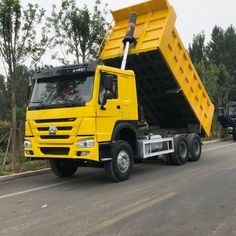 a yellow dump truck driving down the road