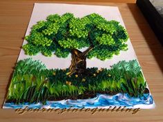 a painting of a tree with grass and water in the foreground on a wooden table