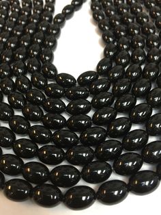 black glass beads are lined up on a white surface