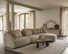 a living room with a large sectional couch and coffee table in front of the window