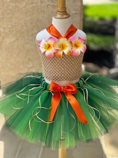 a green tutu skirt with orange and pink flowers on the top, attached to a mannequin