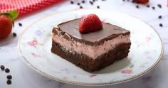 a piece of chocolate cake on a plate with two strawberries