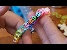 two hands holding colorful bracelets with letters on them and beads in the shape of letters