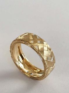 a yellow gold wedding band with woven weaves on the inside and outside, set against a plain white background