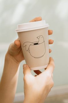 a person holding up a cup with a drawing on it