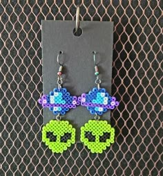 a pair of earrings made out of perler beads and bead, hanging from a hook