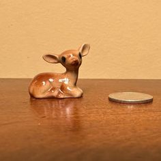 a small deer figurine sitting on top of a wooden table next to a coin