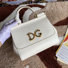 Description DG Medium DG Handbag In Dauphine White For Women 10.2in/26cm DG Rep 1:1 Size: 26 x 21 x 12 cm / 10.2 x 8.3 x 4.7 inches (Length x Width x Height) Medium handbag from the DG line in Dauphine Front flap with hidden snap closure and galvanic logo plate in the front Top handle and adjustable and removable shoulder strap Internal zip pocket and smartphone pocket Metal studs on the bottom Comes with logoed Dust Bag Includes dust bag. This product is of the best quality. Dog Bags, Medium Handbags, Dog Bag, Evening Clutch Bag, Tote Backpack, Fashion Handbags, Evening Bags, Mini Bag, Snap Closure