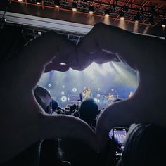 a person making a heart with their hands in front of an audience at a concert