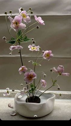 a white vase filled with pink flowers on top of a table