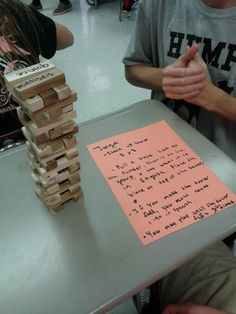 a person sitting at a table with a stack of wooden blocks