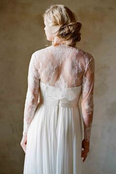 the back of a woman's wedding dress with sheer sleeves and an open neckline