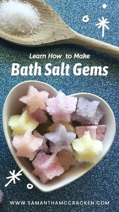 a heart shaped bowl filled with bath salts on top of a blue counter next to a spoon