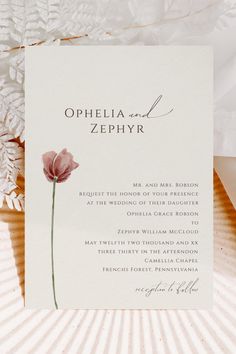 an open lettered wedding card with a pink flower on it and the words ophelia and zephyrr written in curs