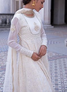 This look features an ivory anarkali set. The closed neck, full sleeves set has a yoke with an embroidered motif and a flowy ghera. Inspired by the royal palaces, it is embellished with mirror, threadwork, pearls, zardozi and sequins all over. A matching net dupatta with scallop border and bootis completes the look. Composition: Anarkali - Viscose georgette, Dupatta - Soft net, Churidar - Lycra Care: Dry Clean Only and Vacuum Storage This product can be customised for colour, sleeves, length of blouse and neck design Delivery : 2 weeks as the product is hand crafted. For more information and sizes please contact fabiliciousfashion@gmail.com or visit our Copenhagen studio.About the Designer : Renee Label was created in 2013,by the talented sister duo Pooja and Karuna, is a culmination of th Anarkali Sets With Pearl Embroidery In Cream, Cream Sets With Pearl Embroidery For Eid, Anarkali Cream Sharara With Pearl Embroidery, Festive Cream Sharara With Pearl Embroidery, White Traditional Wear With Pearl Embroidery For Festive Occasion, Festive White Traditional Wear With Pearl Embroidery, Anarkali Style Georgette Sherwani For Festive Occasions, Festive Cream Anarkali Set With Pearl Embroidery, Anarkali Sherwani With Mirror Work For Reception