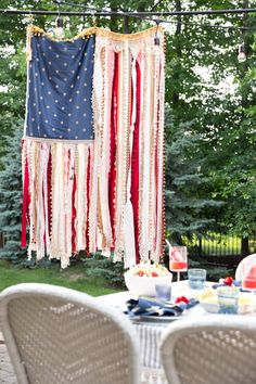 an american flag hanging from a string over a table with chairs and plates on it