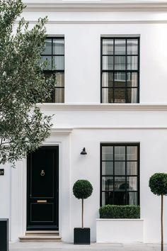 Minimalist white stucco house with striking black window frames and seamless indoor-outdoor connection White Exterior Black Windows, European Inspired Homes, White Two Story House, Farmhouse With Black Accents, White Building Exterior, Modern Stucco Exterior, Stucco Farmhouse, European Contemporary Home