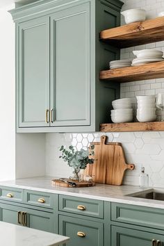 a kitchen with green cabinets and white tile backsplash, wooden cutting board on the counter