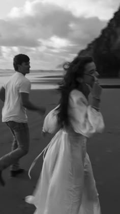 black and white photograph of two people walking on the beach, one holding a cell phone to her ear