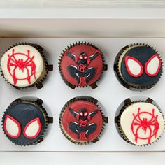 six cupcakes decorated with red and black icing in a box on top of a table