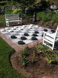 a checkerboard chess board in the middle of a garden with two white chairs