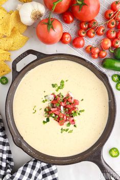 a skillet filled with cream sauce and garnished with tomatoes, onions, green peppers, and tortilla chips