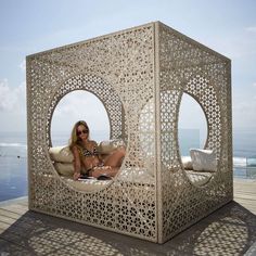 a woman is sitting on a couch made out of wood and white wickers