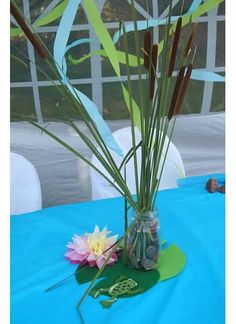 a vase filled with water and flowers on top of a blue table cloth covered table