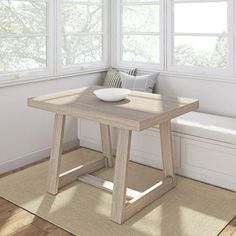 a table with a bowl on it sitting in front of a window next to a bench