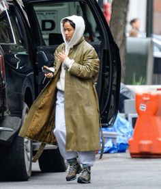 a woman is walking down the street while looking at her cell phone and wearing a coat