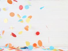 multicolored confetti and streamers are falling from the sky on a white background