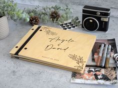 an open wedding album with photos, pen and camera next to it on a table