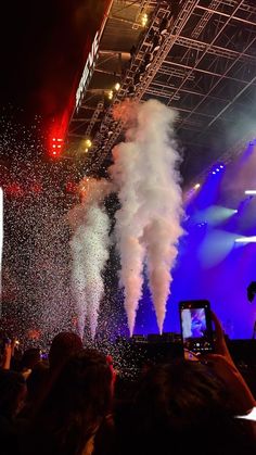 people are taking pictures with their cell phones as fireworks go off in the air at an outdoor concert