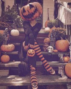 a woman dressed up as a witch sitting on steps with pumpkins