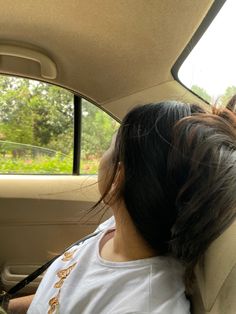 a woman sitting in the back seat of a car with her head out the window