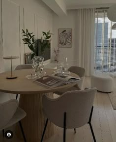 a dining room table with chairs and vases on it in front of a window