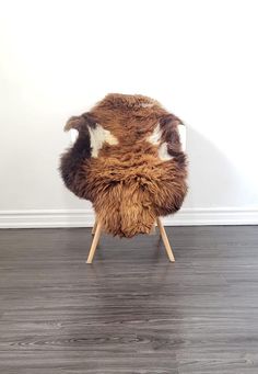 a brown and white chair sitting on top of a hard wood floor next to a wall