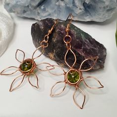 Handmade green Peridot earrings wrapped with tarnish-resistant copper. Wire wrap flower design. Green Peridot Known as the extremem gem, this crystal is associated with the sun. Peridot has been prized since the earliest civilizations for its protective powers to drive away the forces of darkness. Peridot is also highly beneficial for attuning to and regulating the cycles of one’s life Chakra: Heart | Astrology: Virgo, Leo, Scorpio | Numerology: 5, 6 | Planet: Venus | Element : Earth **Crystals Wire Wrap Flower, Numerology 5, Earth Crystals, Flower Wire, Planet Venus, Element Earth, Astrology Virgo, Peridot Earrings, Leo Scorpio