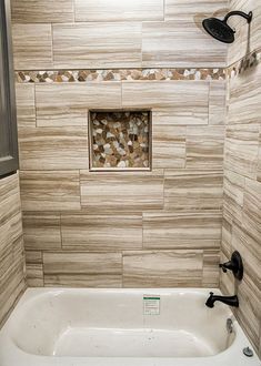 a bathroom with a white bath tub sitting next to a shower head and hand held faucet